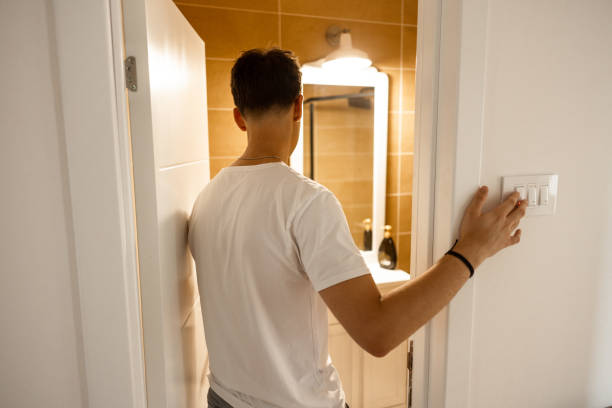 Unrecognizable teenage boy, turn on the light switch for the bathroom