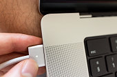 Close-up of teenage boy, inserting Max safe charger into USB port on the MacBook Pro