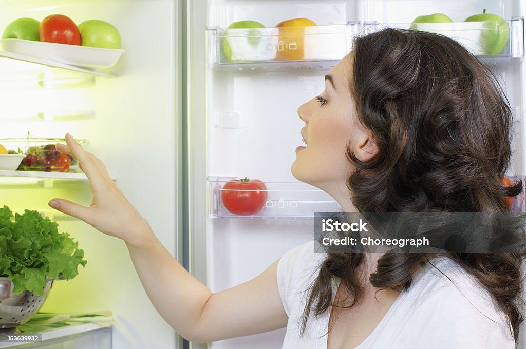 fridge with food a hungry girl opens the fridge Refrigerator Stock Photo