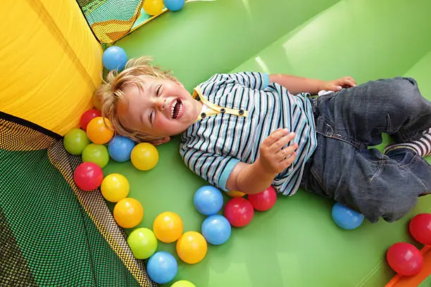 2 year old boy smiling on an inflatable bouncy castle
