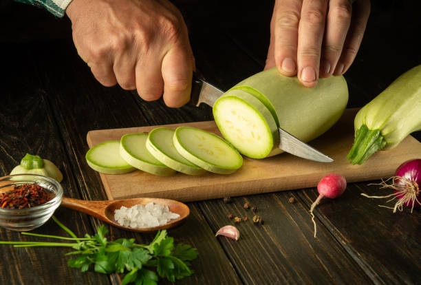 istock The chef cuts zucchini with a knife before roasting with vegetables and spices. Working environment on the kitchen table 1536421300