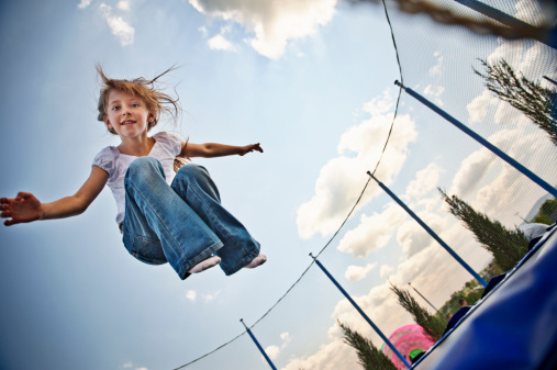 Little girl having fun jumping on trampoline.Slightly soft.