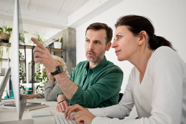 Mature woman and man working on computer in the office