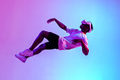 african american male gamer in virtual reality glasses flies in the air and falls in neon lighting, guy plays with vr