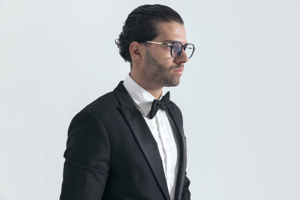 Young man in tuxedo against white background.