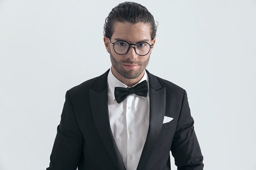 Young man in tuxedo against white background.