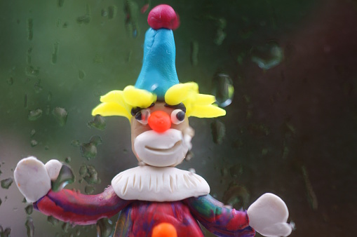 A toy clown on the background of wet glass.