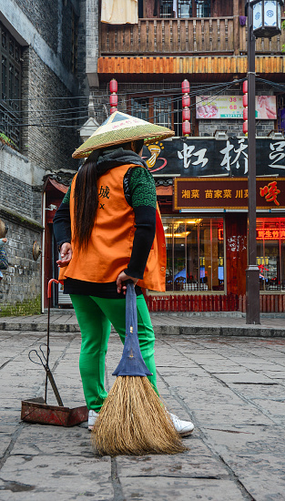 Hunan, China - Nov 5, 2015. Road sweeper worker cleaning city street at Fenghuang Ancient Town in Hunan, China.