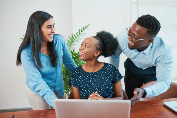 istock Three diverse colleagues discuss and laugh around laptop in office 1536530462