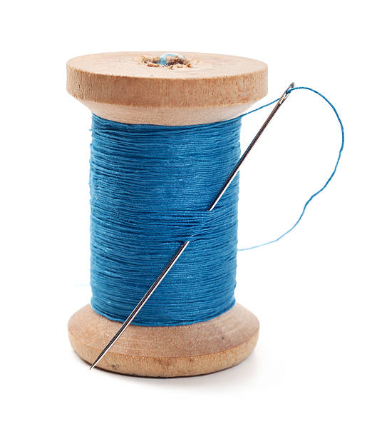 A spool of blue thread with a needle in it Spool of thread with needle isolated on white sewing needle stock pictures, royalty-free photos & images