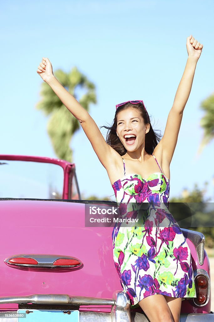 Summer vacation car road trip Summer vacation car road trip freedom concept. Happy xwoman cheering joyful in summer dress during holiday travel in pink vintage car. Beautiful young mixed race Caucasian / Chinese Asian female model in Havana, Cuba. Cuba Stock Photo