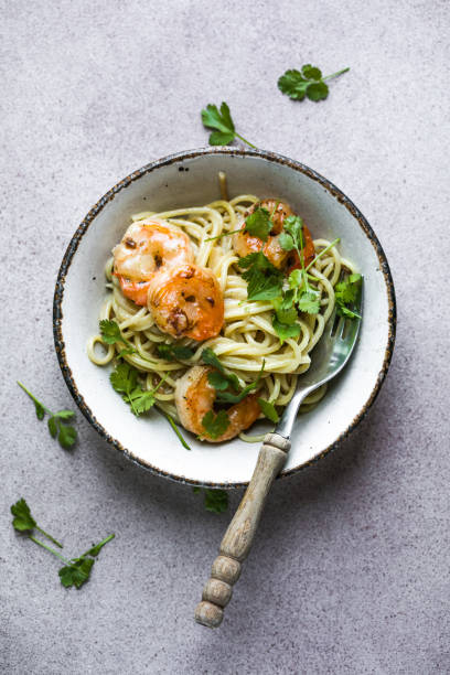 istock Several portions of cooked and twisted Spaghetti pasta with king prawn tails 1536568721