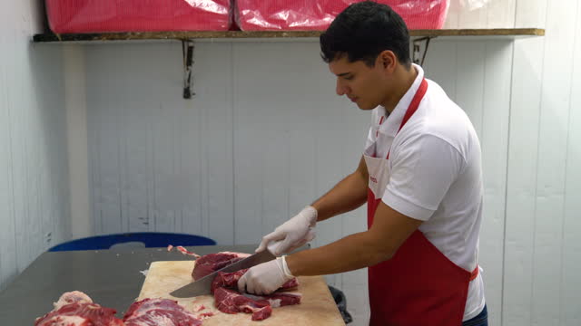 Male young butcher slicing meat at the butchery