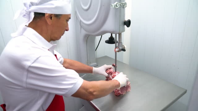 Butcher cutting a block of pork with an electric saw
