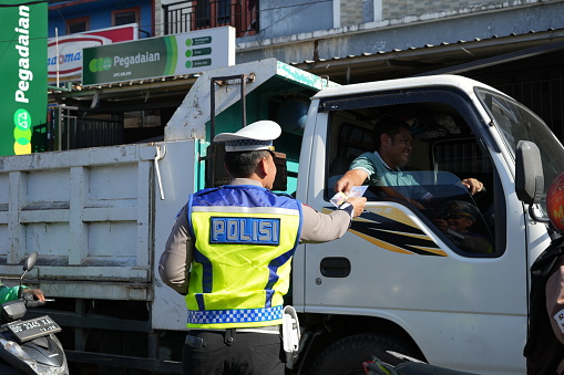 Makassar, Indonesia - July 12 2023: Police officers are controlling traffic on the streets and socializing proper traffic rules to motorbike and car drivers