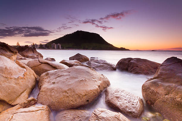 Mount Maunganui Sunset Mount Maunganui is a town in the Bay of Plenty, New Zealand, located on a peninsula to the north of Tauranga. It was independent from Tauranga until the completion of the Tauranga Harbour Bridge in 1988. mount maunganui stock pictures, royalty-free photos & images