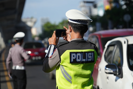 Makassar, Indonesia - July 12 2023: Police officers are controlling traffic on the streets and socializing proper traffic rules to motorbike and car drivers