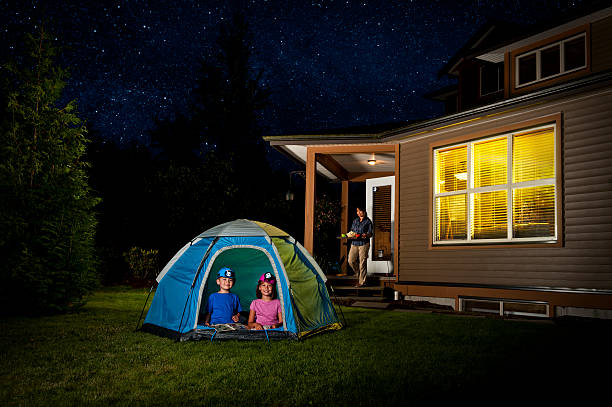 Children camping in a tent in the backyard