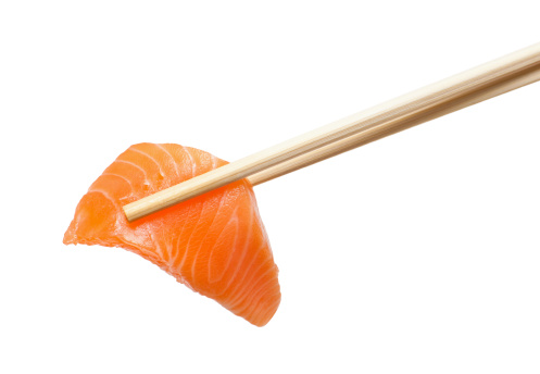 Isolated sliced raw salmon with chopsticks holding it