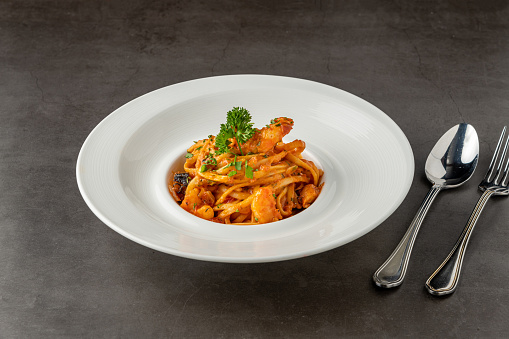 Shrimp spaghetti on white porcelain plate on black stone table