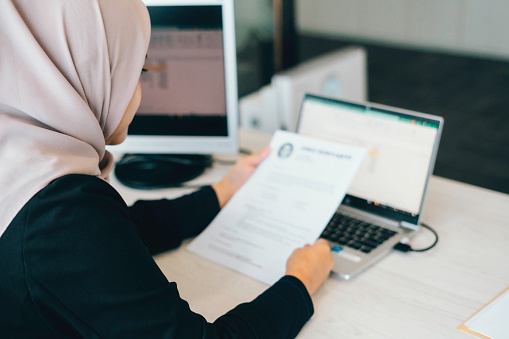 business muslim woman reading a resume on paper to hire correct personnel