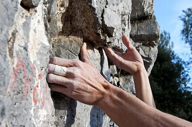 Hands of a man climbing on limestone, Muzzerone Mountain, Italy