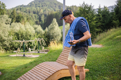 Elderly man sitting down on the bench after a good morning exercise at the outdoor gym
