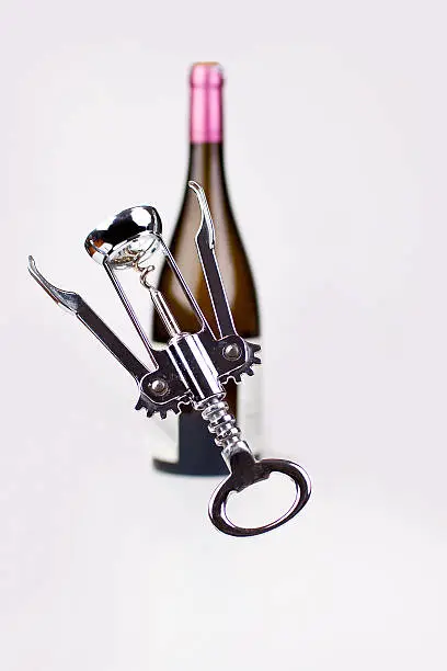 corckscrew in foreground, wine bottle in back ground