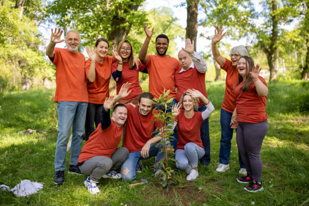 Volunteers waving to camera after planting a tree in a forest