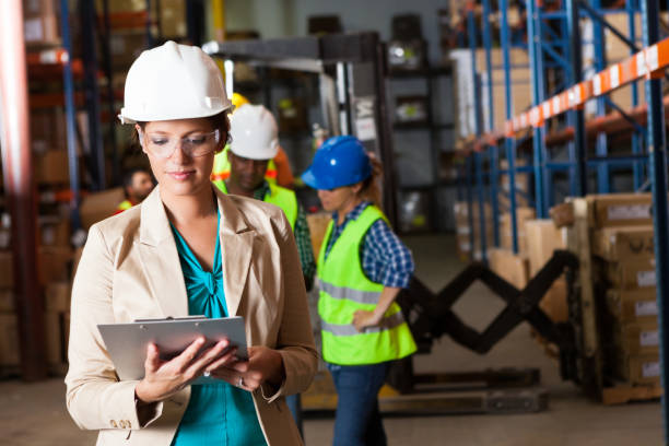istock Warehouse manager examining inventory list with forklift operators in background 153678599