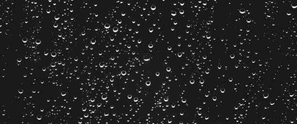 istock Atmospheric minimal grayscale backdrop with rain droplets on glass. Wet window with rainy drops and dirt spots closeup. Blurry minimalist monochrome background of dirty window glass with raindrops. 1536790237