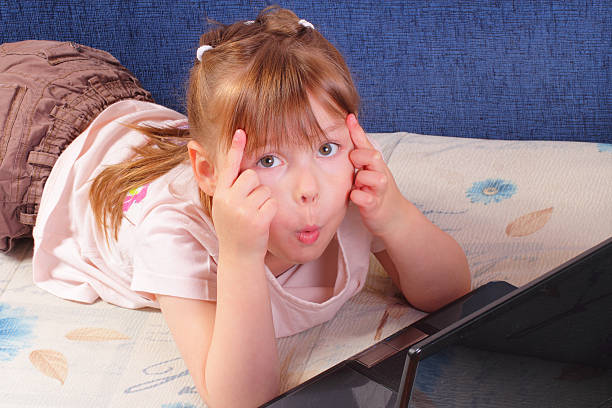 Funny little girl with laptop stock photo
