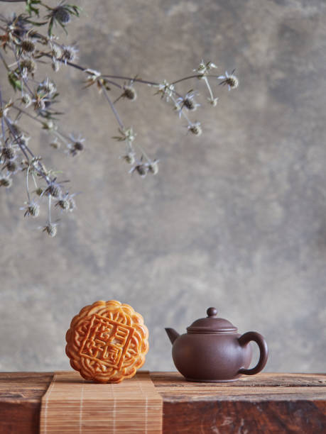 istock Moon cake on bamboo mat and small teapot on wood. Blurred gray background, branches and dried flowers. Mid-autumn festival composition. Front view, copy space. 1536796577