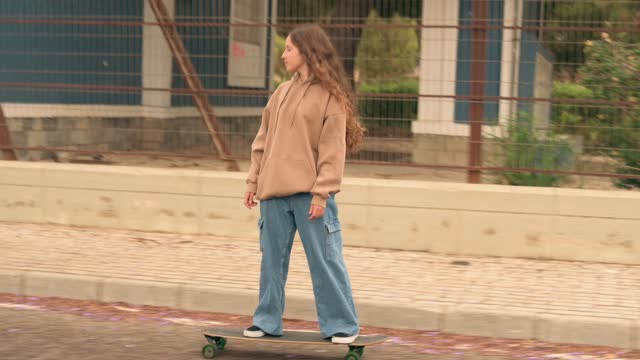 Young woman skateboarding down the road of a street