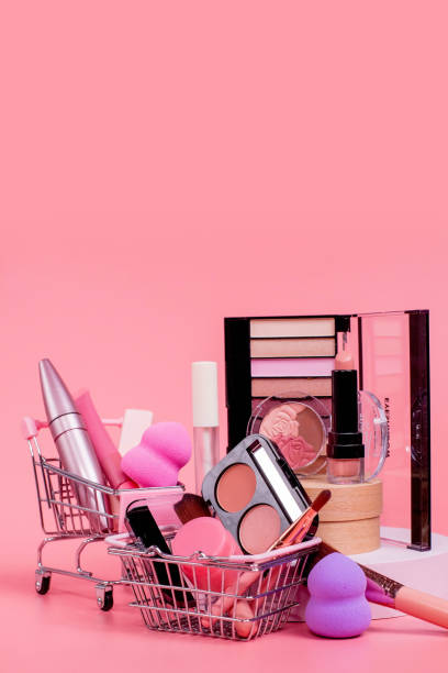 istock Creative concept with shopping trolley with makeup on a pink background. Perfume, sponge, brush, mascara, eye shadow, lip gloss in the basket 1536820131