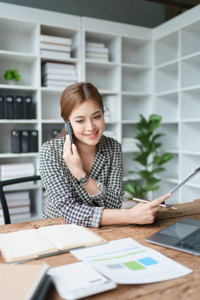 istock Consultant, advisor, Asian business woman working on the computer and using smartphone mobile talking work financial and marketing business planning company profits, marketing planning budget. 1536829035