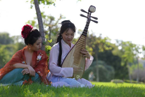 Young ladies under tree relaxing and playing a Mandarin Instrument