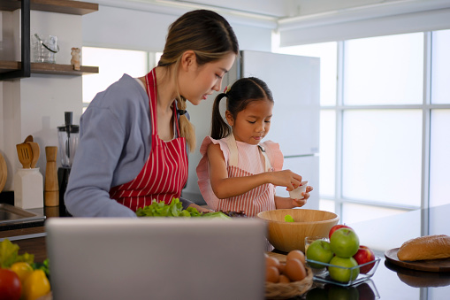 Mother and daughter make a meal at kitchen. Family relationship concept.