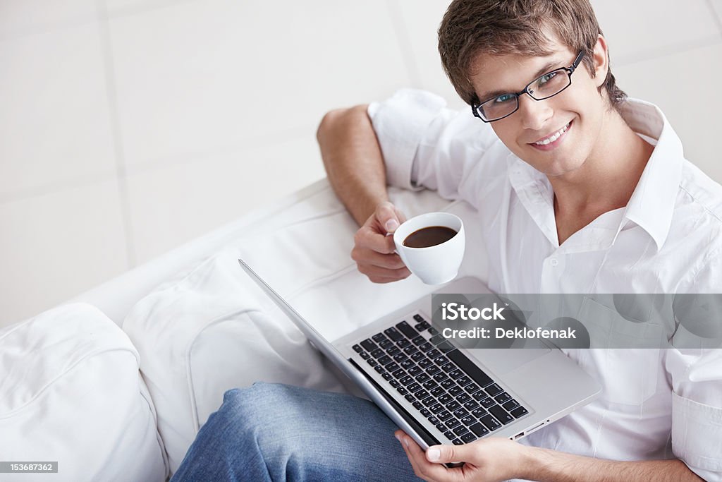 Working A young man with a cup and laptop 20-24 Years Stock Photo