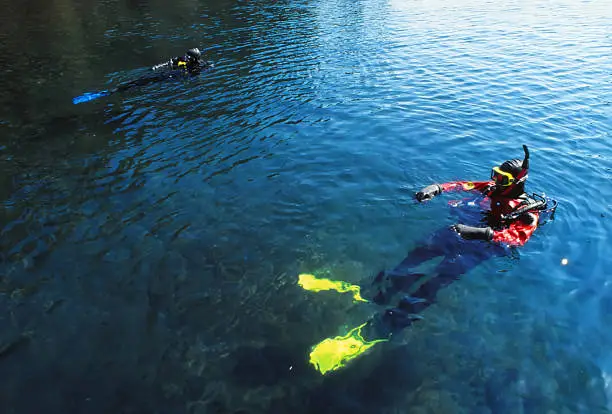 Scuba divers in dry suits prepare to dive the clear waters of  Waldo Lake.