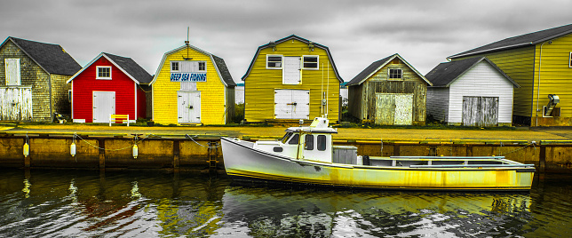 Boat docked on an overcast morning, in front of several barn-type structures, boat landing at New London, Prince Edward Island, Canada.