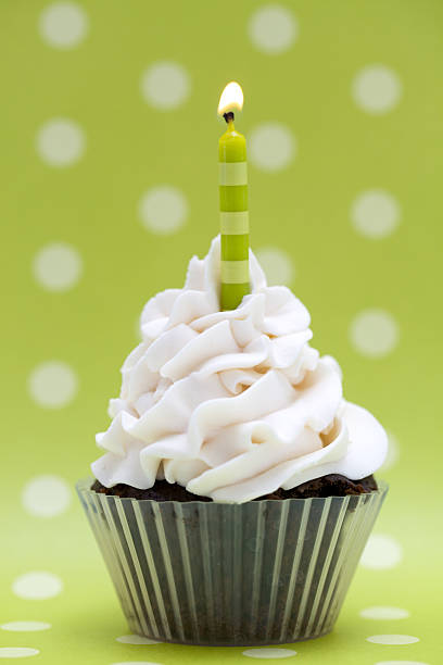 istock Chocolate cupcake with white icing with a green candle 153689338