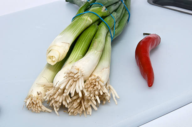 Spring onions & chilli on chopping board stock photo