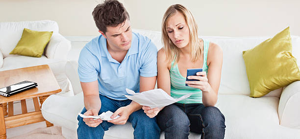 istock Concentrated young couple calculating bills sitting on the sofa 153690130