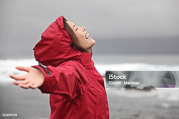 A Woman In A Red Rain Poncho Enjoying The Rain Stock Photo - Download Image Now - Beach, Rain, Women