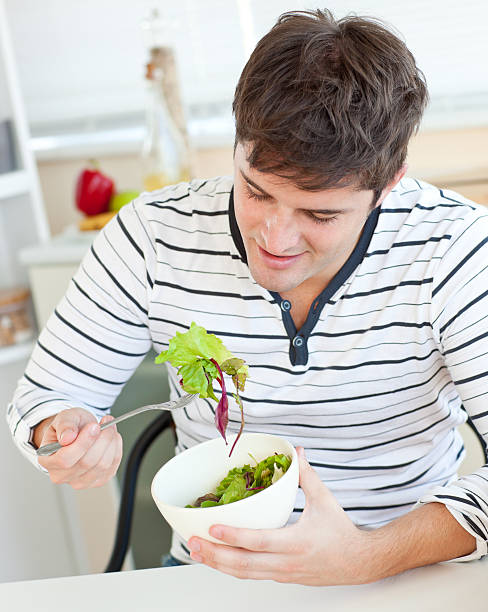 istock Delighted young man eating a healthy salad in the kitchen 153693642