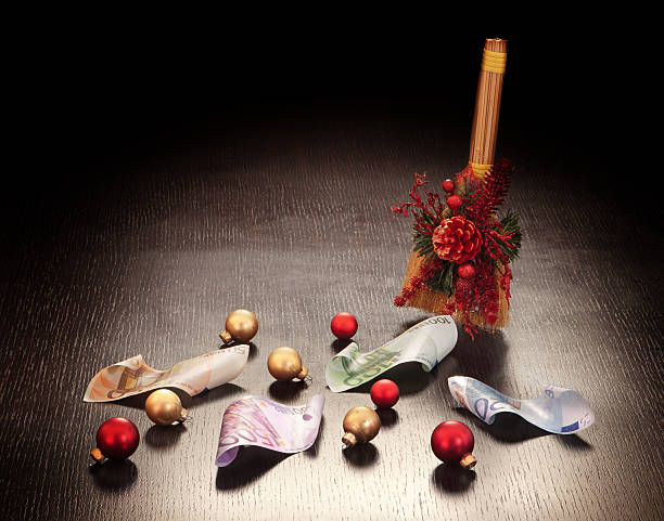 Christmas business decoration: euros swept with broom on dark background. Stock photo of Christmas and New Year business decoration: euros swept with broom on dark background with glowing glass balls . Wealth and financial success concept. euro bill in a christmas ornament stock pictures, royalty-free photos & images