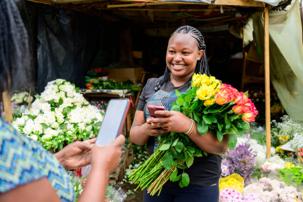 frau, die sich darauf vorbereitet, kontaktlos für blumen zu bezahlen - flower market flower shop market flower stock-fotos und bilder