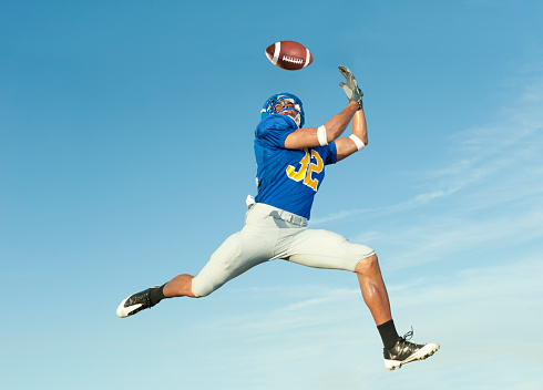Football player catches ball in midair.