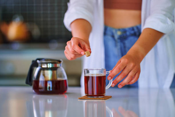 istock Female adding cane brown sugar cube to black tea at home kitchen 1536961072